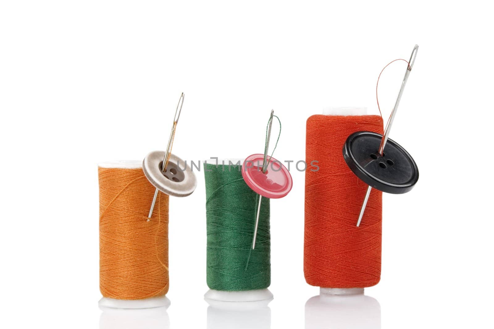 three colored spool with needles and buttons