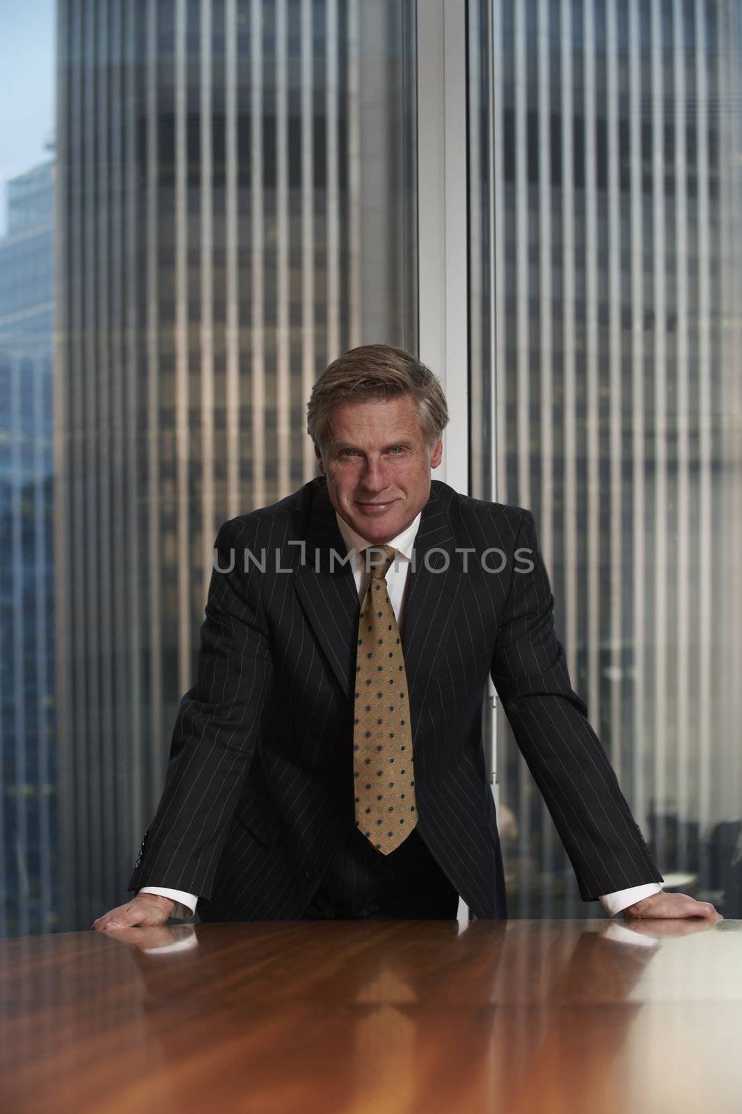 Business man leaning on chair in boardroom looking at camera