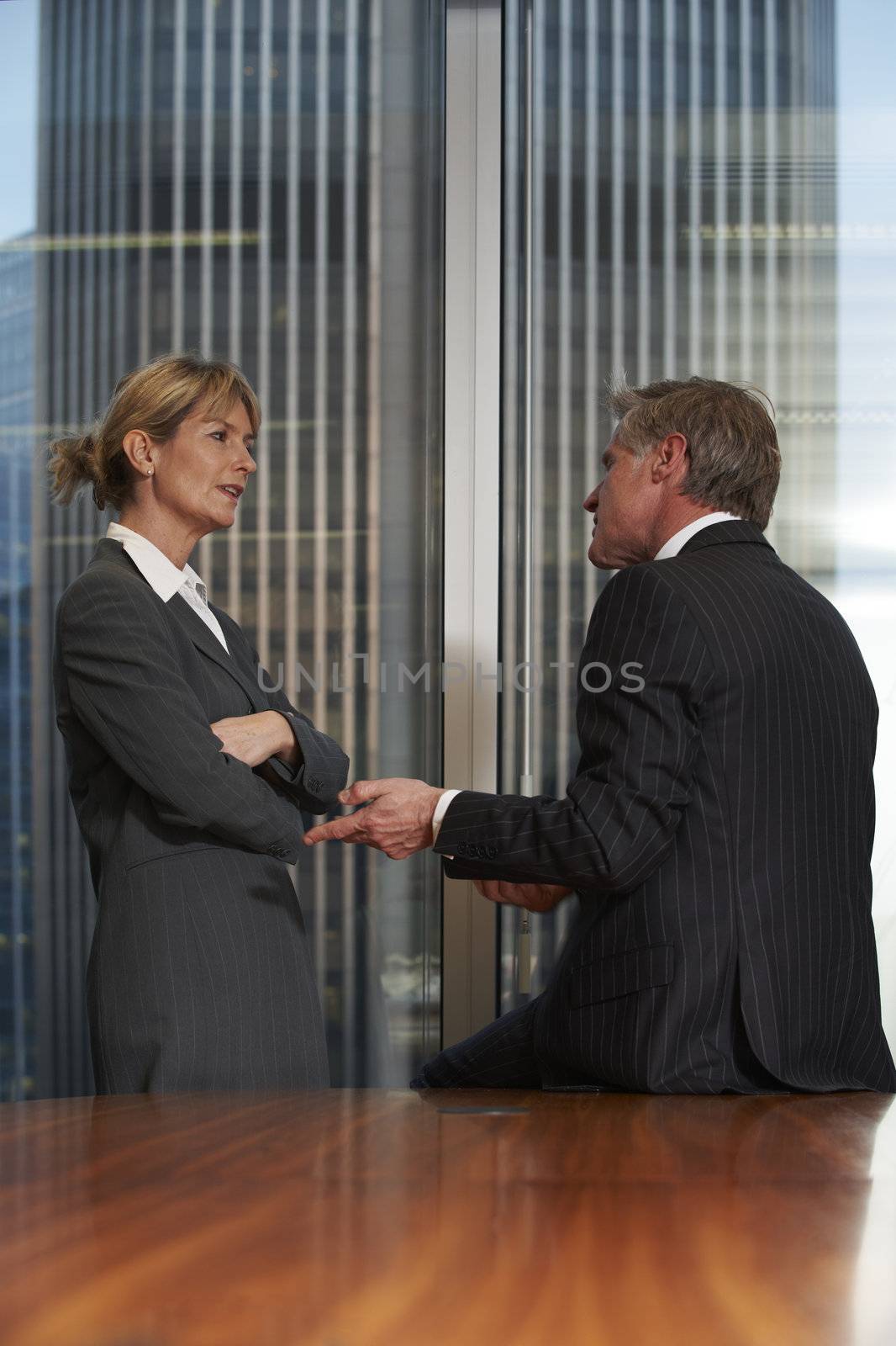 Senior business man and woman in a boardroom having a conversation