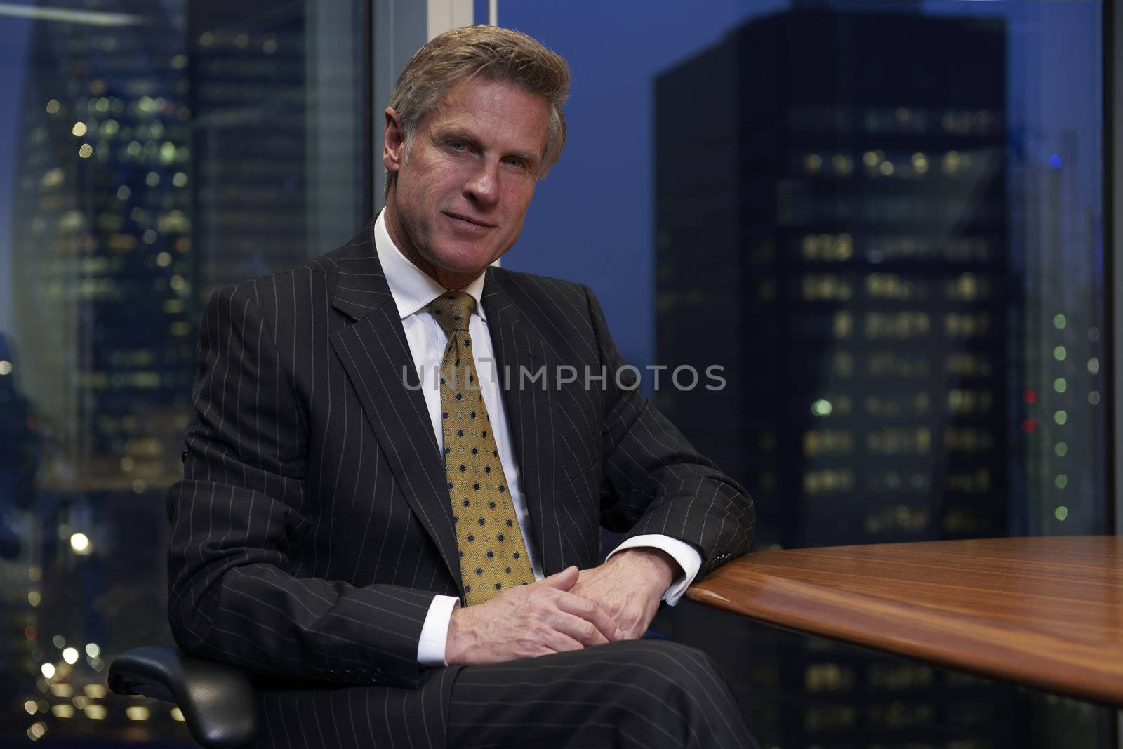 Business man sitting at table in boardroom looking at camera