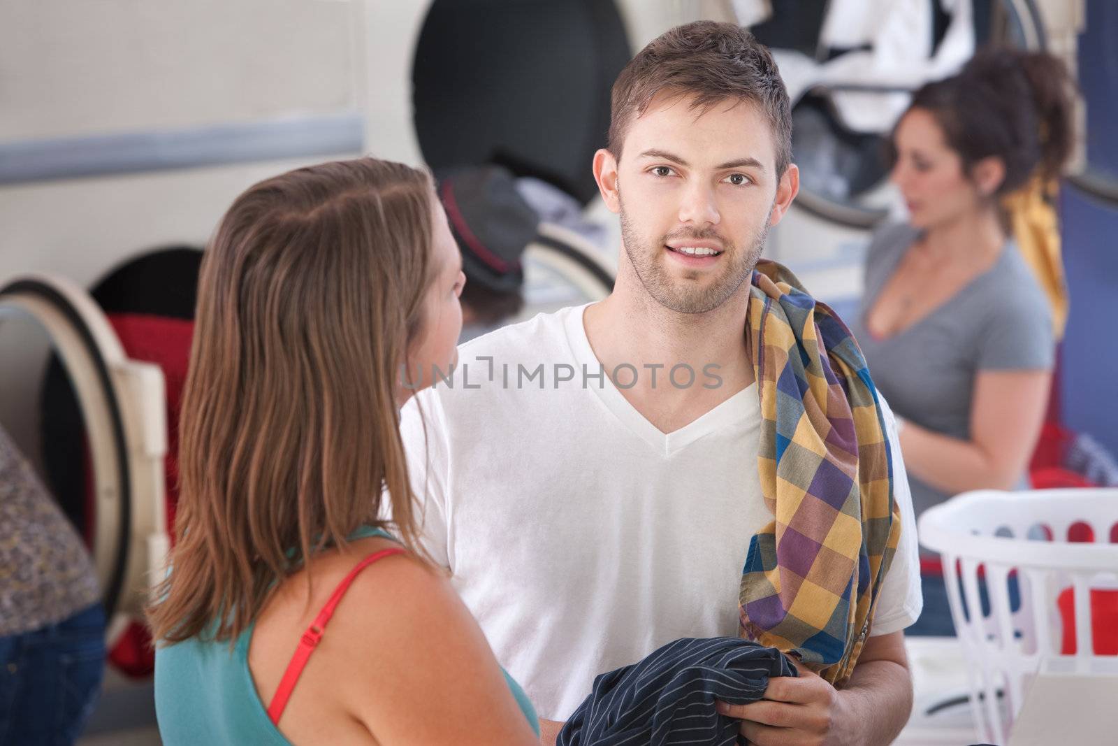 Handsome young Caucasian man with his girlfriend in laundromat