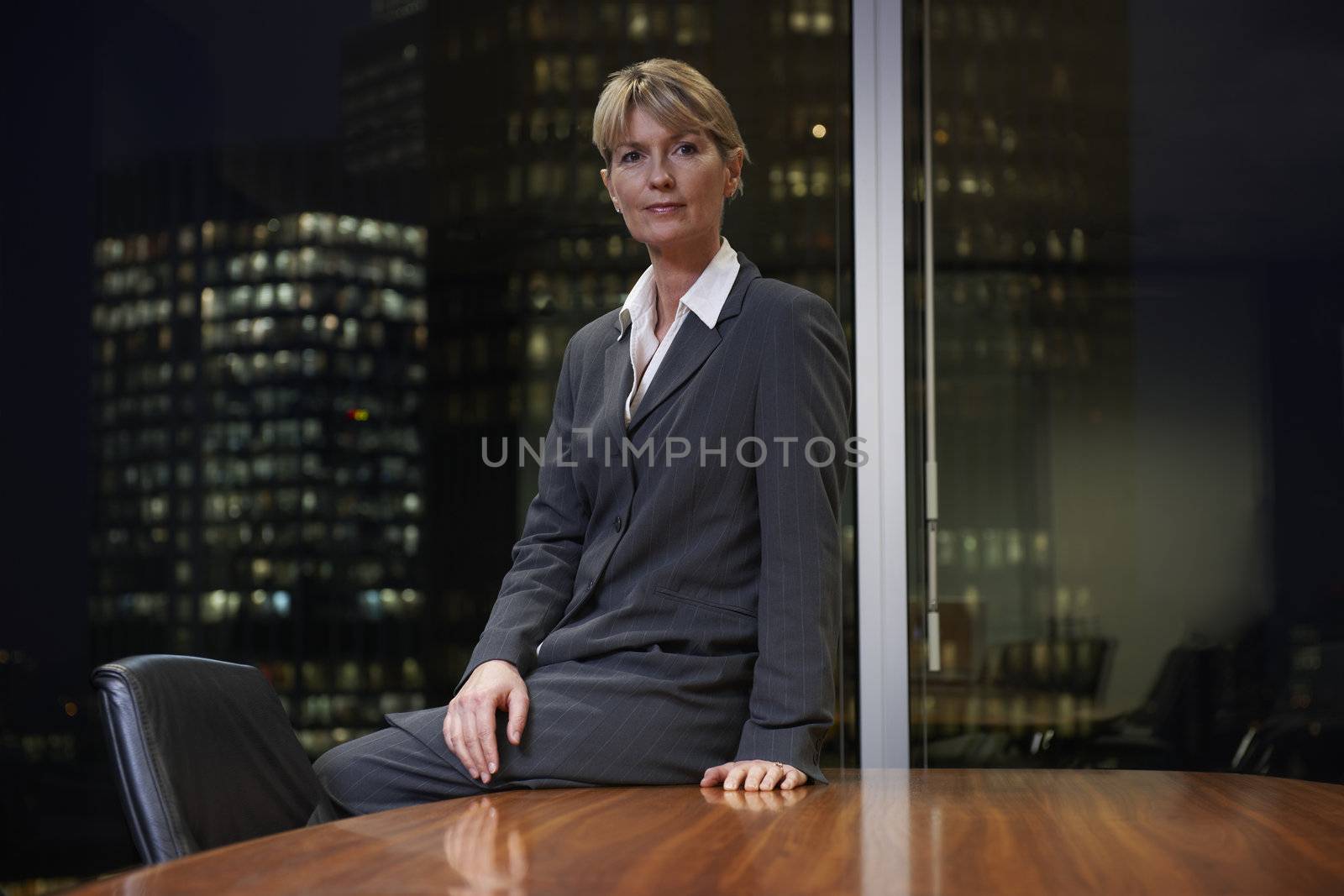 Business woman sitting at table in boardroom looking at camera