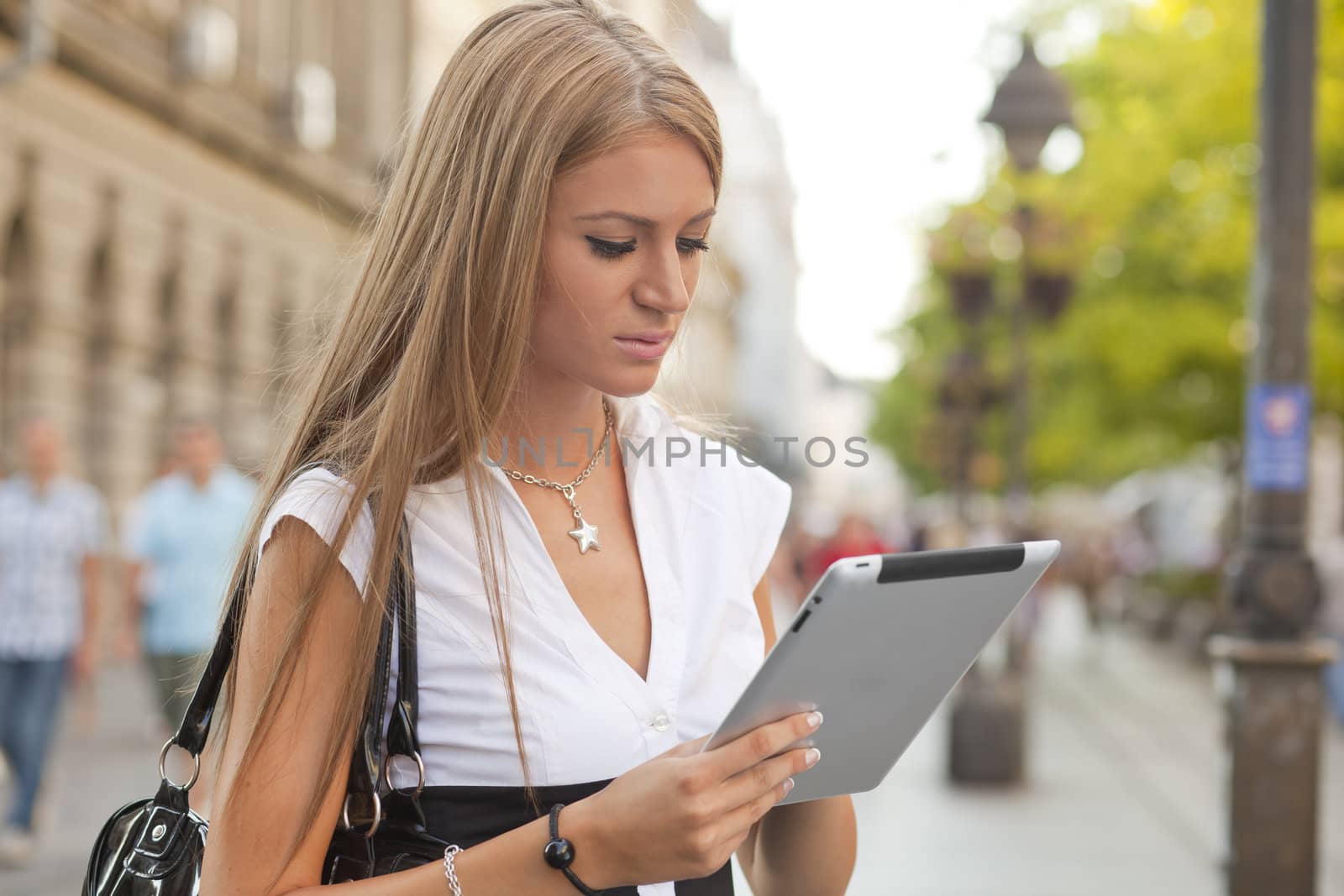 Business Woman with tablet computer walking on urban street by adamr