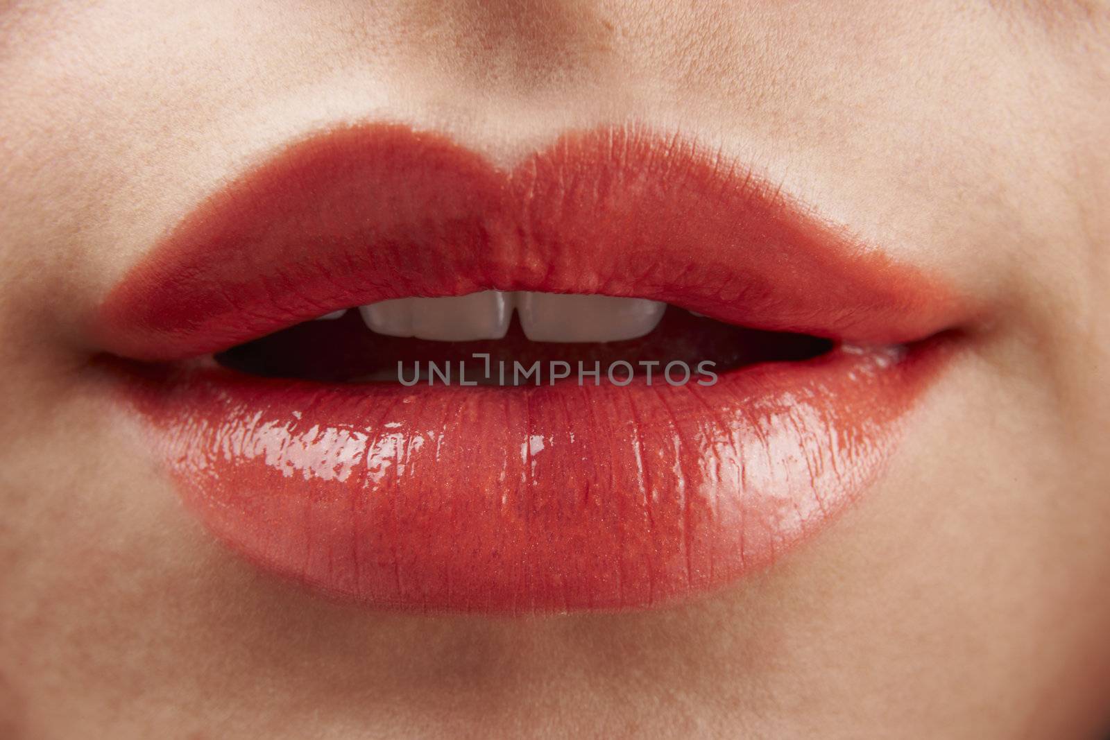 Close-up of womans lips with red glossy lipstick