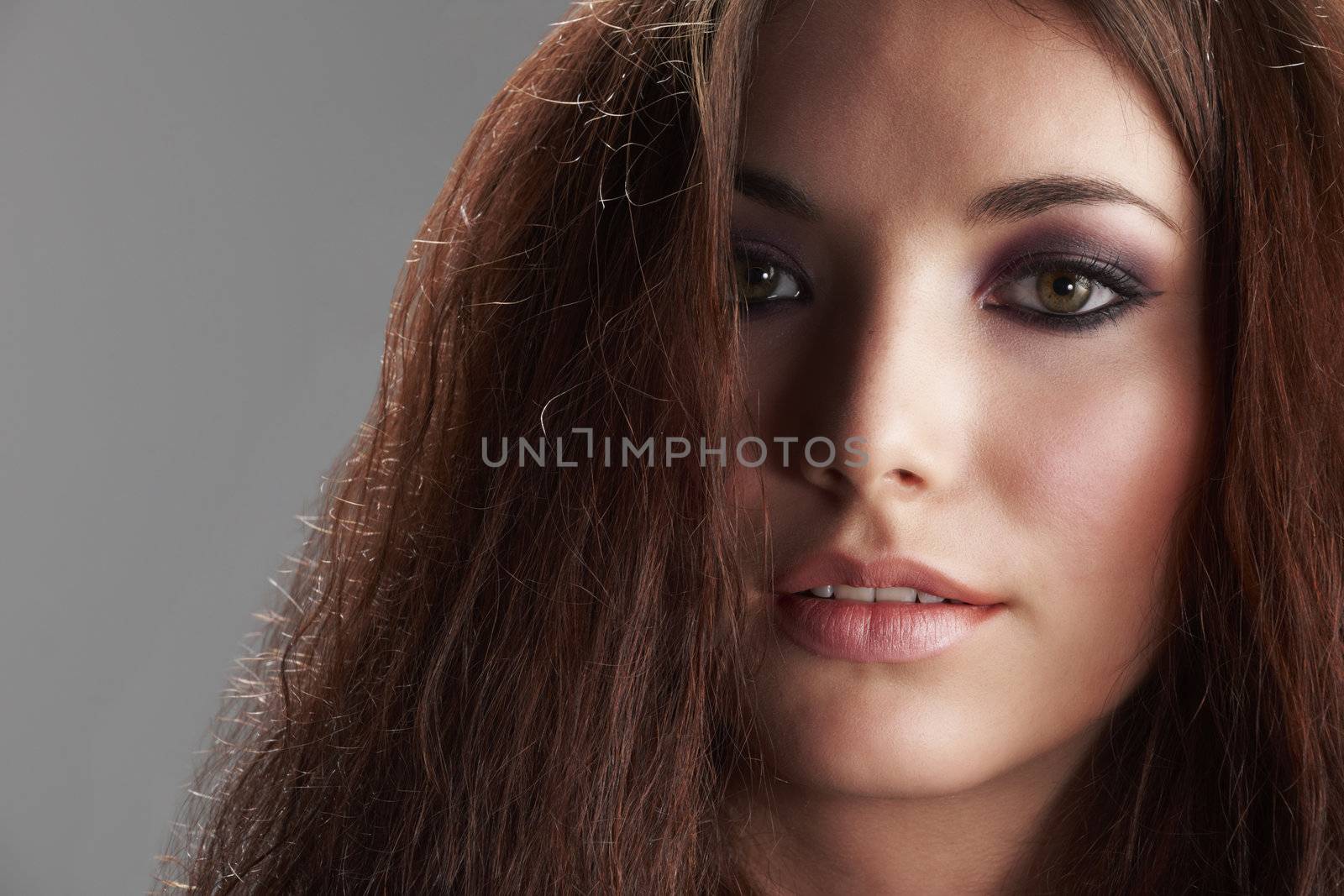 Portrait of beautiful young woman with make-up on grey background