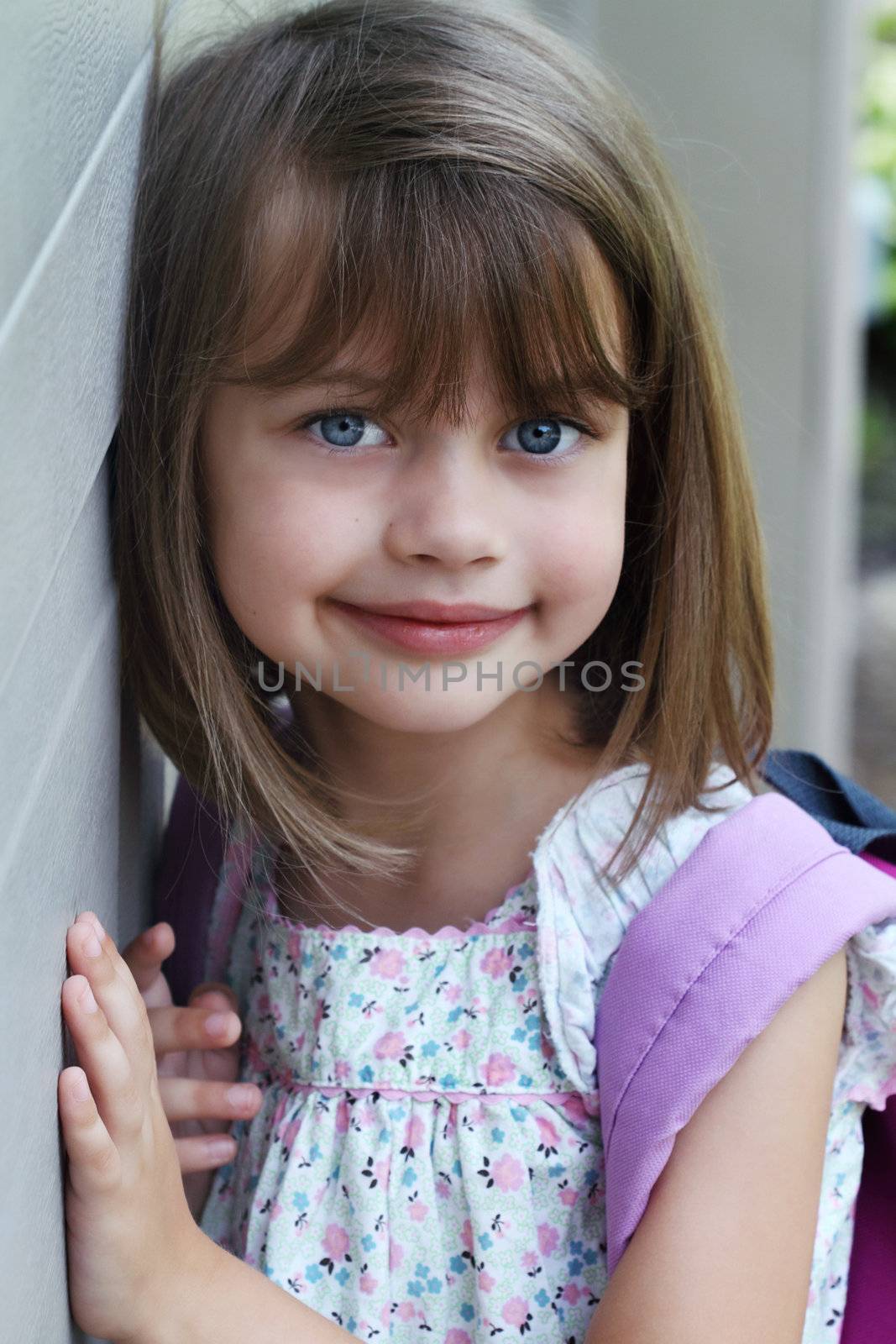 Portrait of a young child carrying a book bag or back pack.