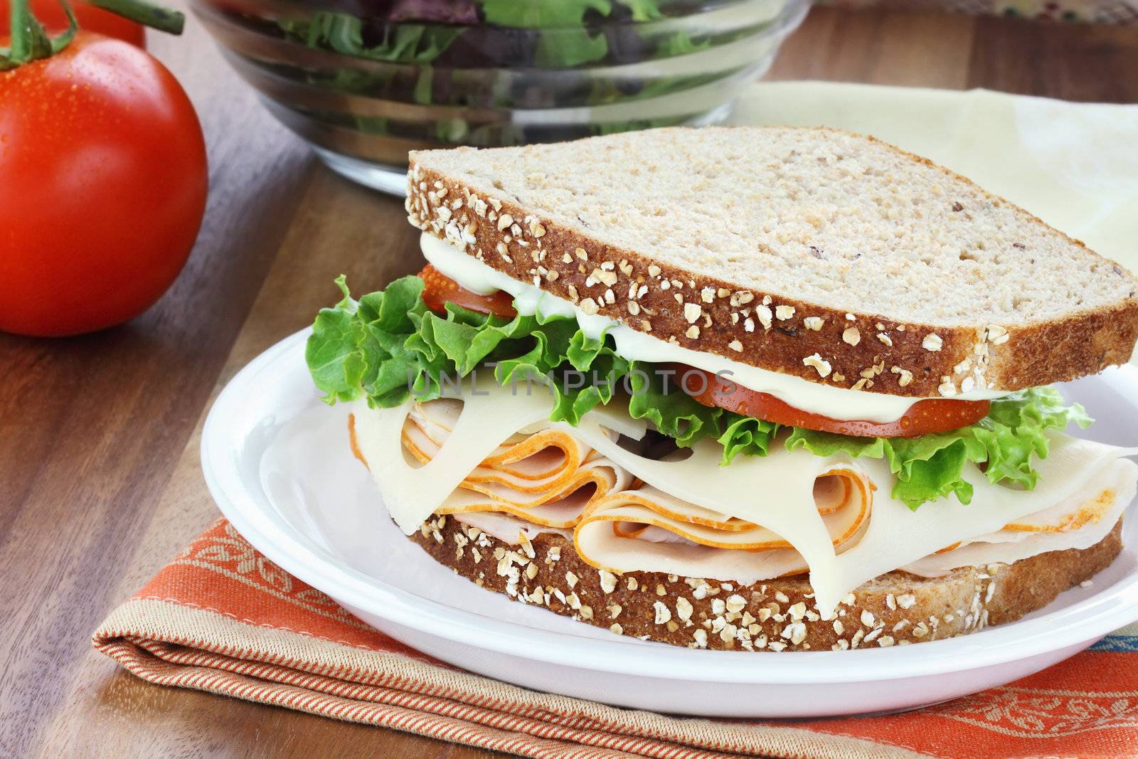 Smoked chicken sandwich with lettuce, tomato and swiss cheese and whole grain bread.
