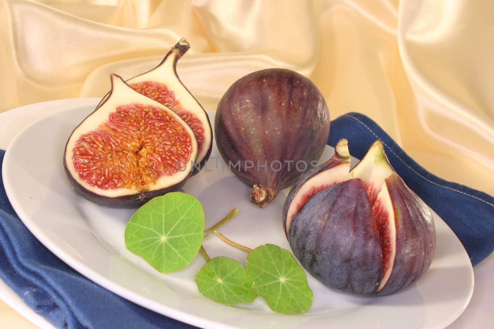 half figs with nasturtium on a white plate