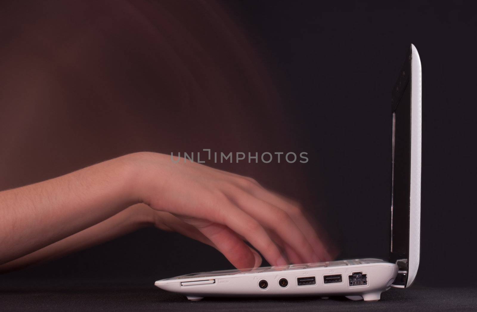 Hands typing in motion on the laptop keyboard by AndreyKr