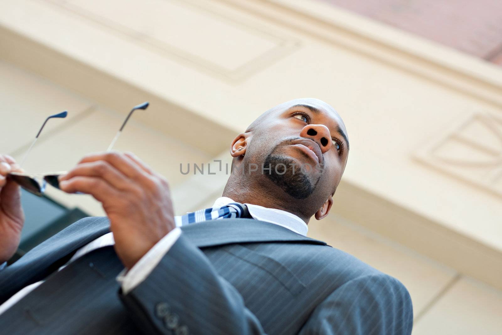 An African American business man wearing his sunglasses and business suit in the city.