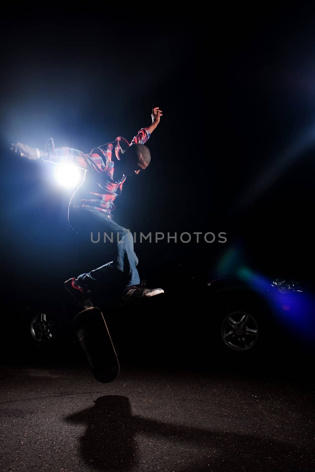 A young skateboarder doing jumping and kick flip tricks under dramatic rim lighting with lens flare. 