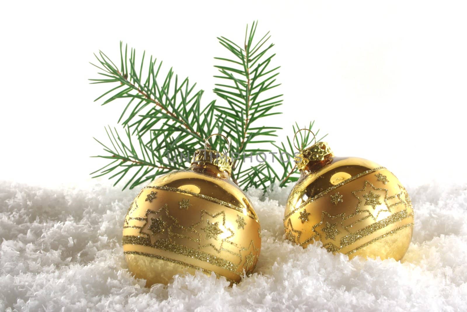 two golden Christmas balls with pine branches lying in the snow