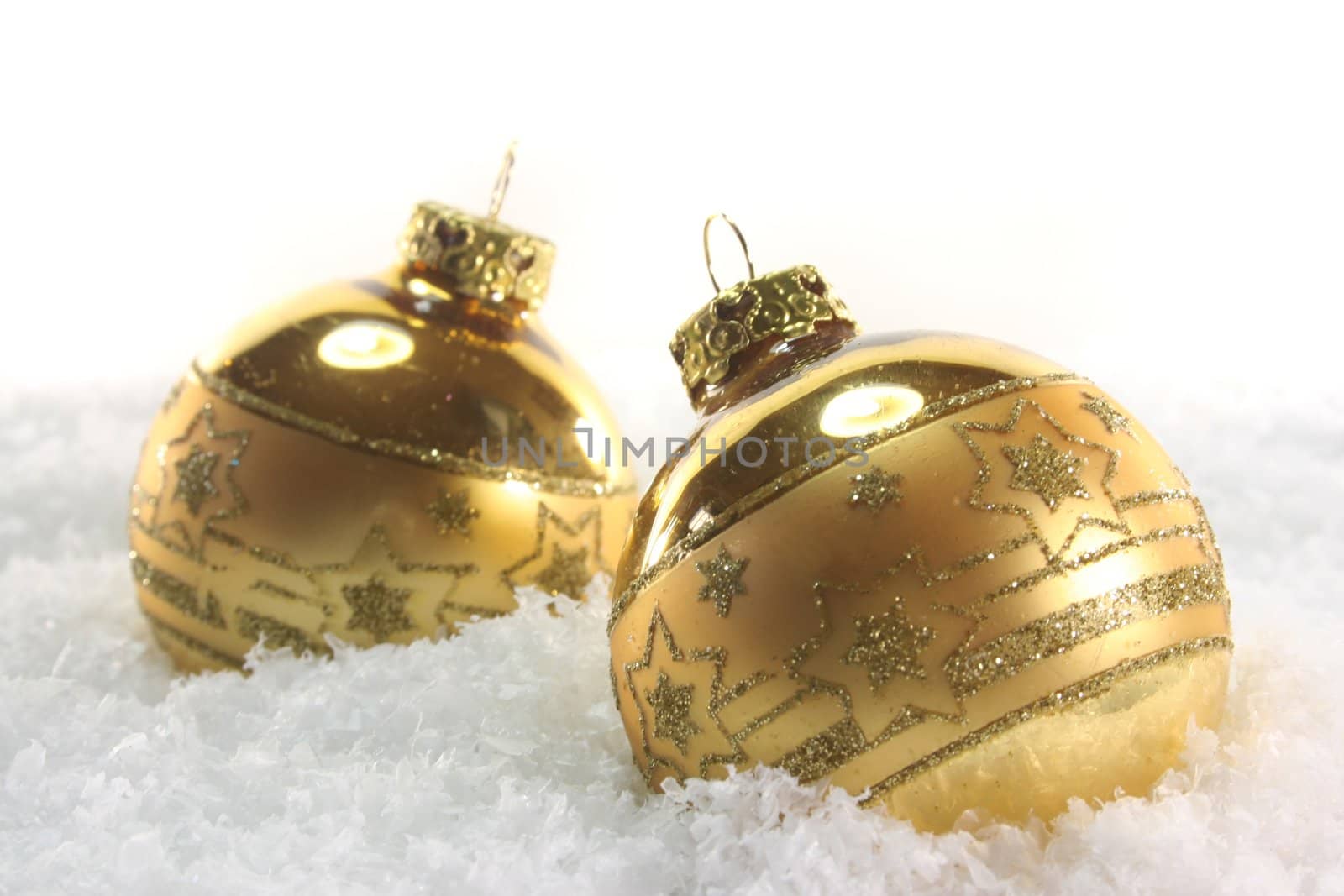 two golden Christmas balls lying in the snow