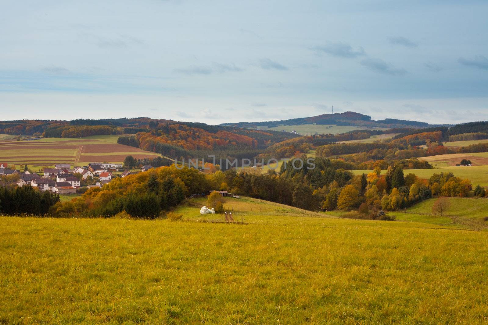 Farmland, small town and forested hills in Eifel, rural Germany.