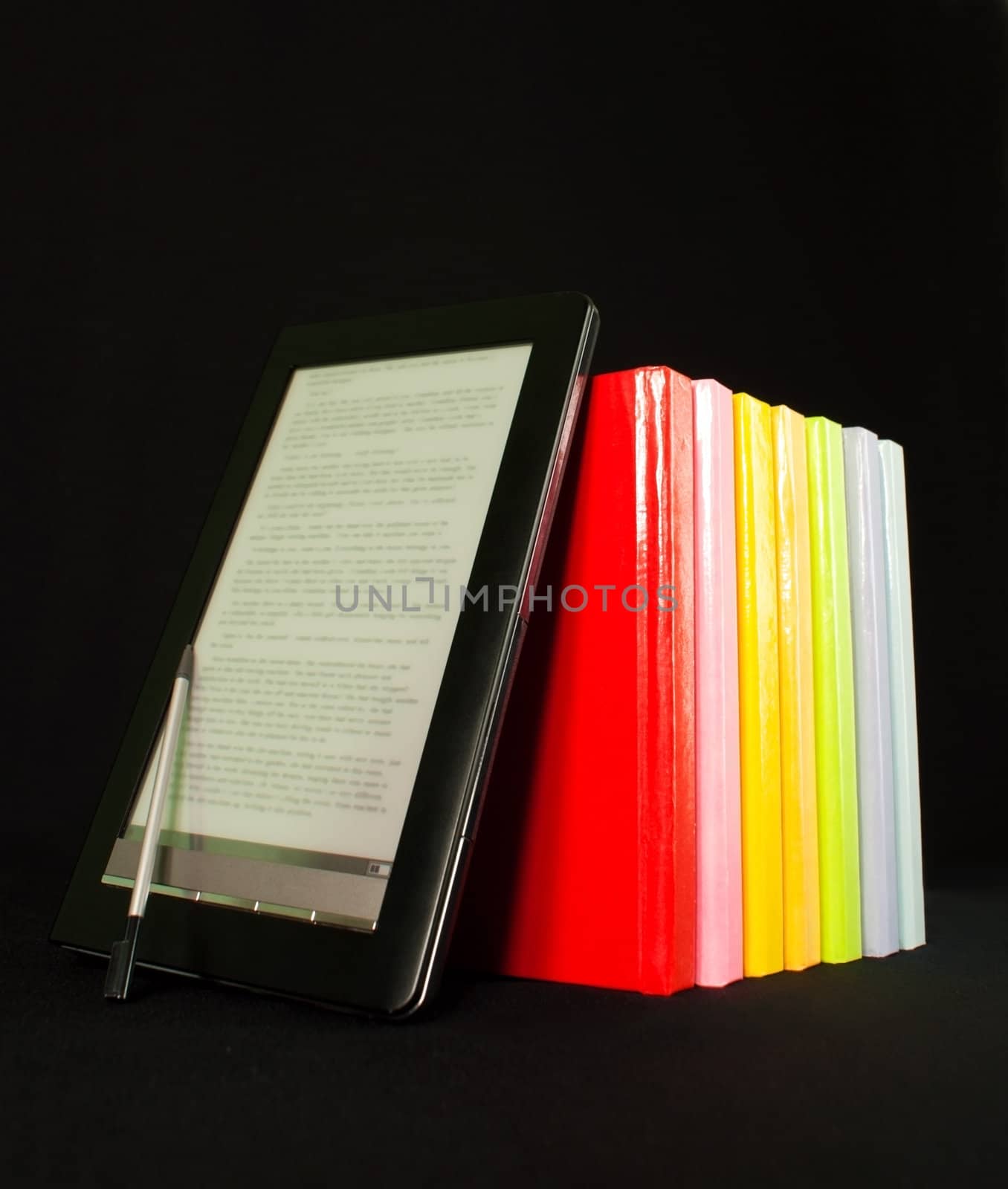 Row of colorful books and electronic book reader on the black background