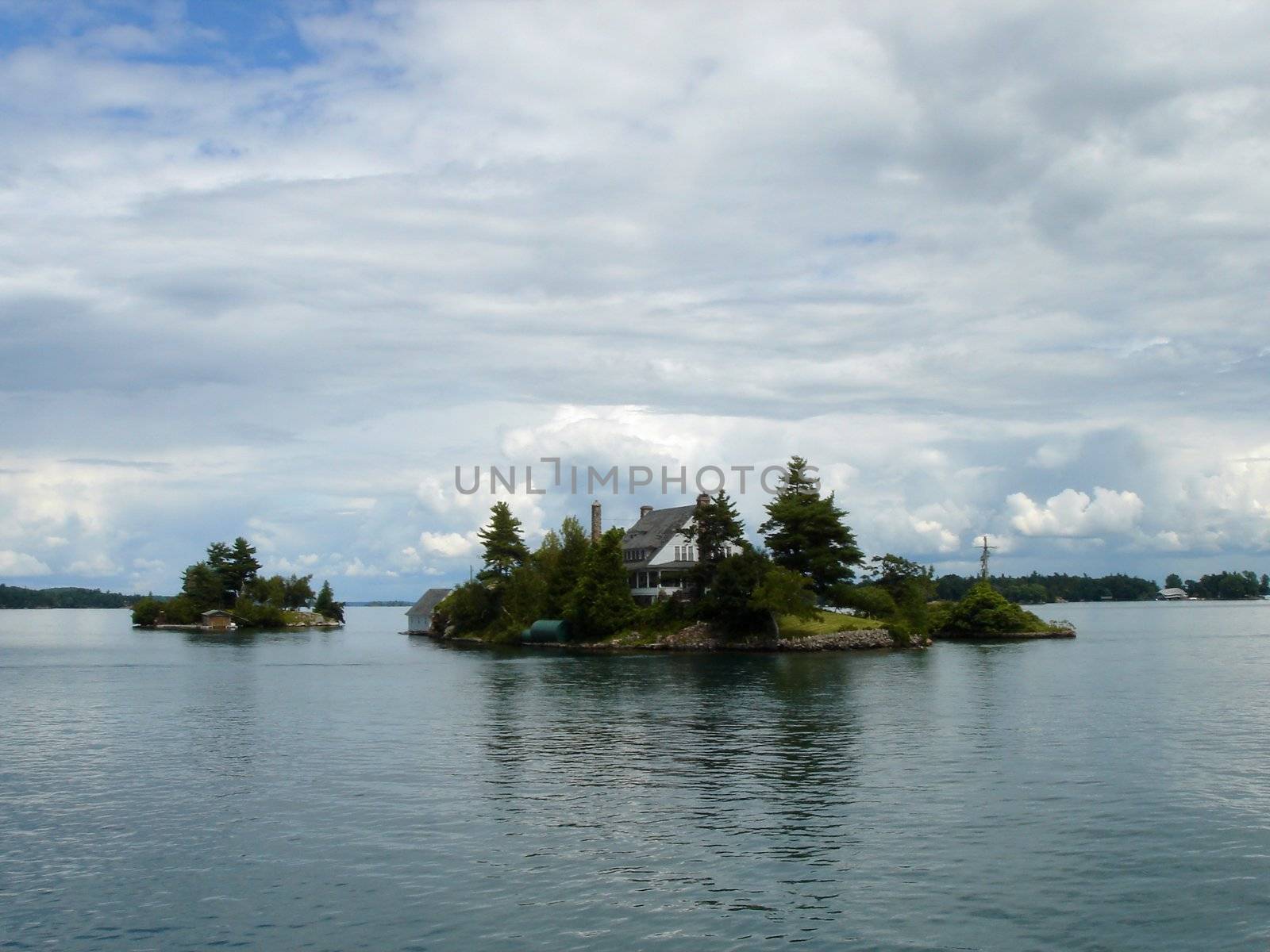 Small island with a house in the middle of thousand islands on Ontario lake, Canada, by cloudy weather