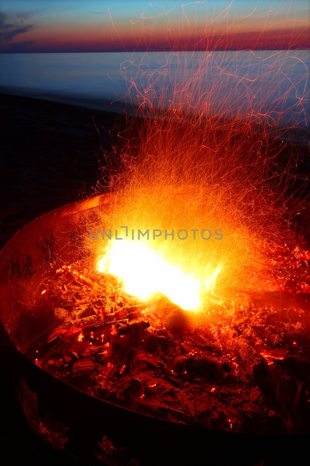 Blazing campfire at sunset along the beautiful beach of Lake Superior in northern Michigan.