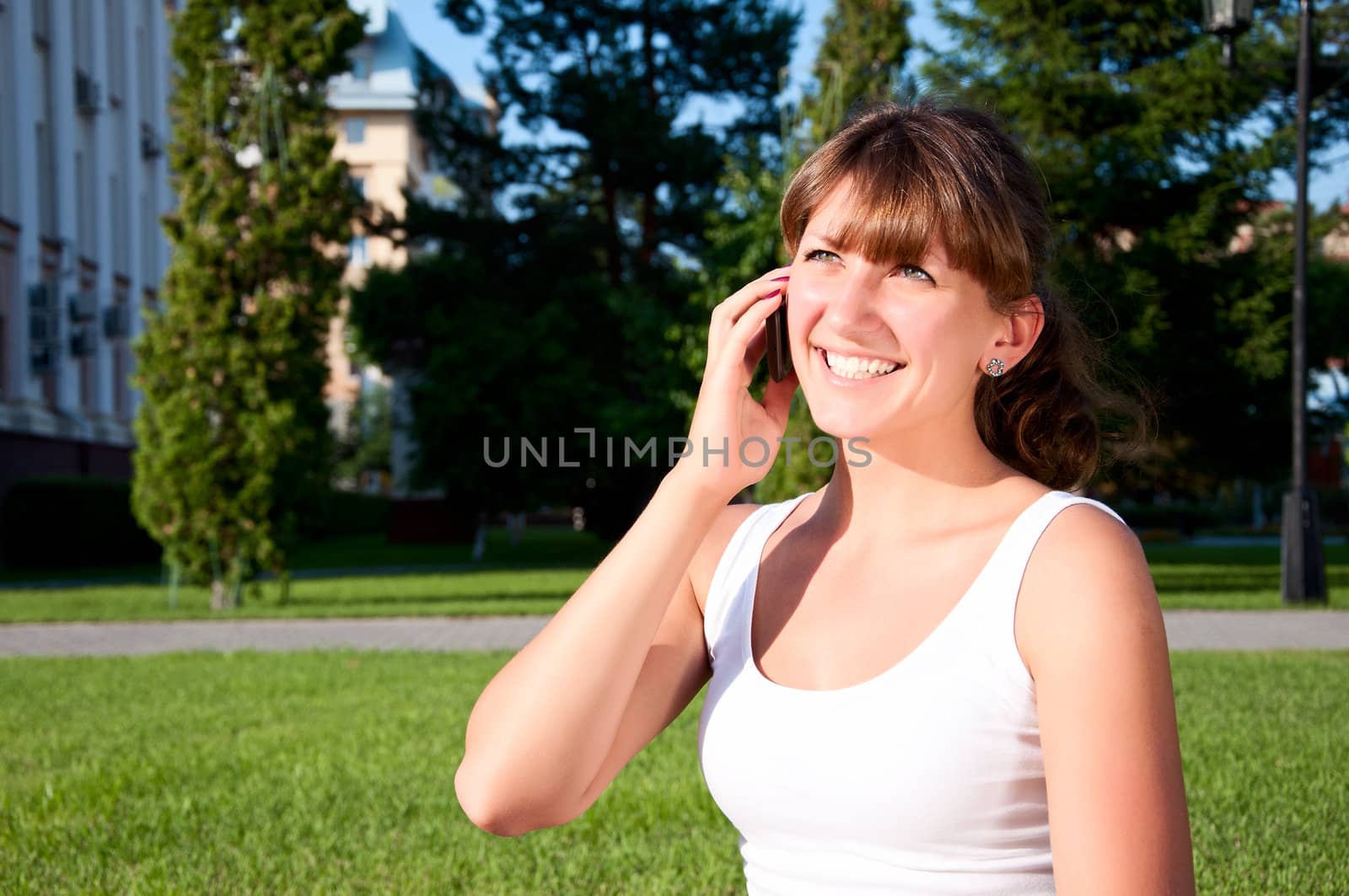 portrait of young woman talking on phone, green grass background