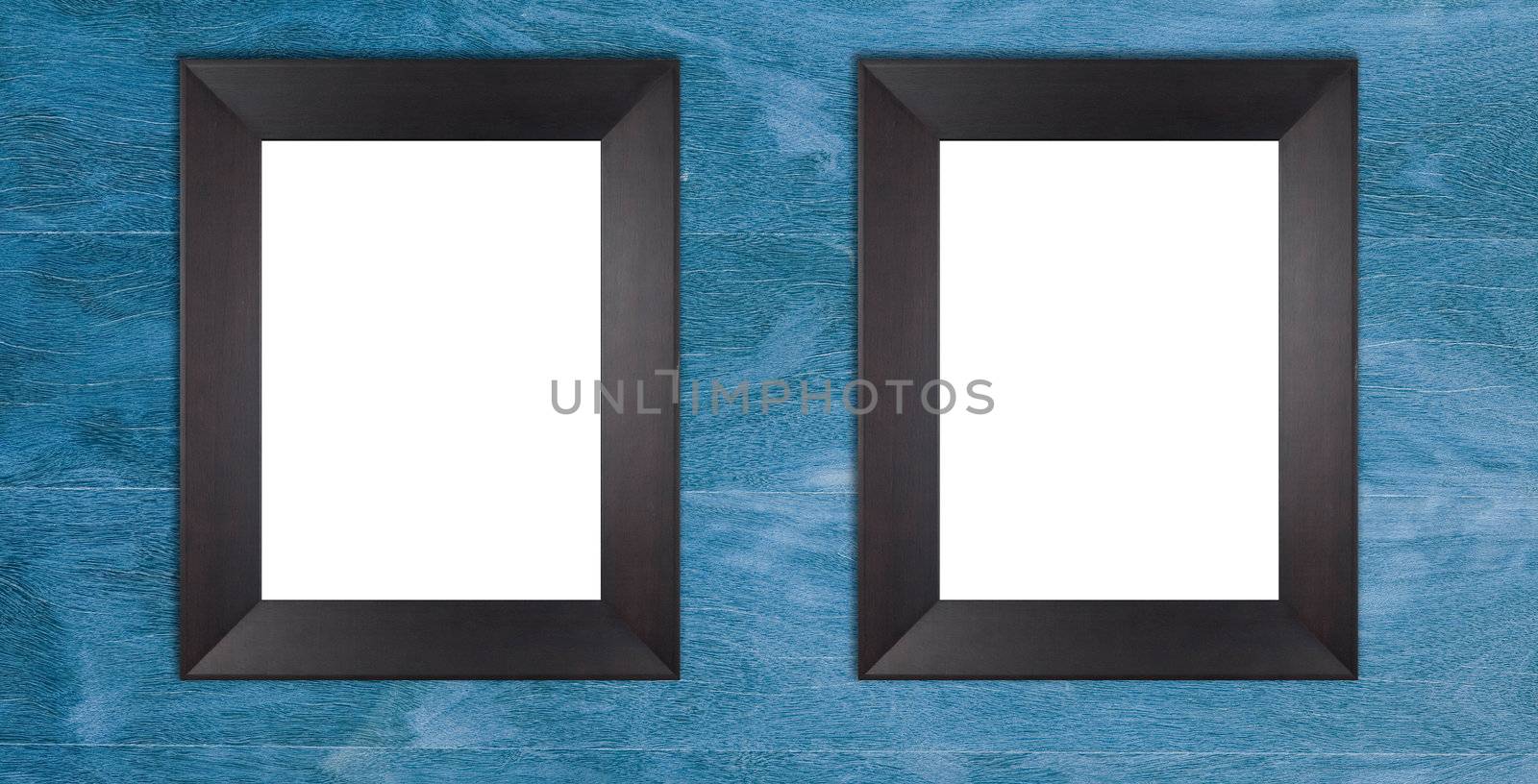 Two blank wooden black frames on blue painted wooden wall.