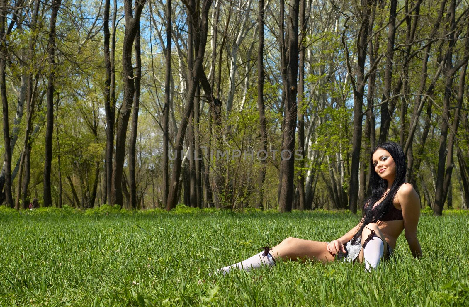 sexy brunette getting spring sunbath, sitting on the green grass