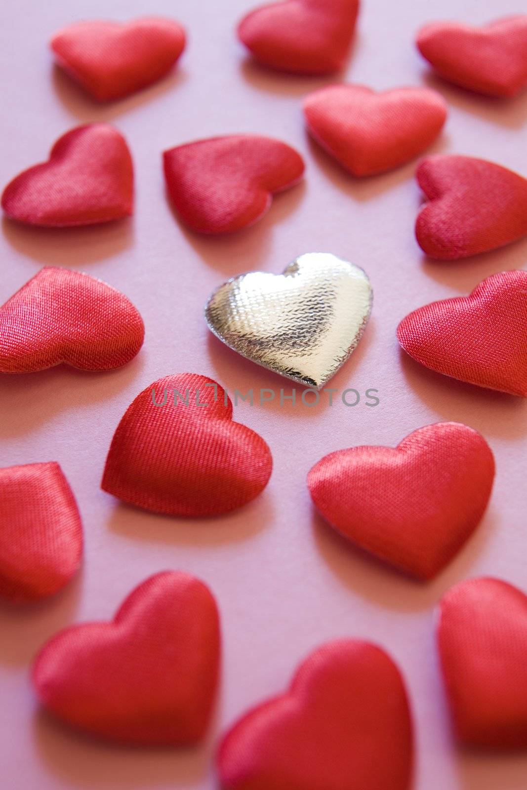 Silver heart amongst red hearts on pink background