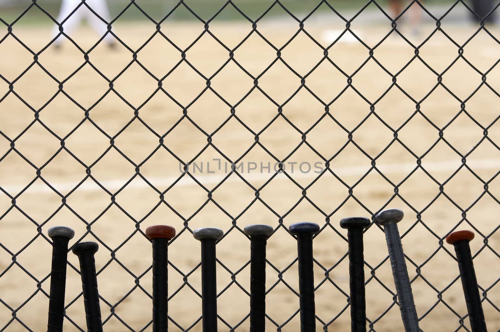 baseball bats learning against dugout fence as game is played