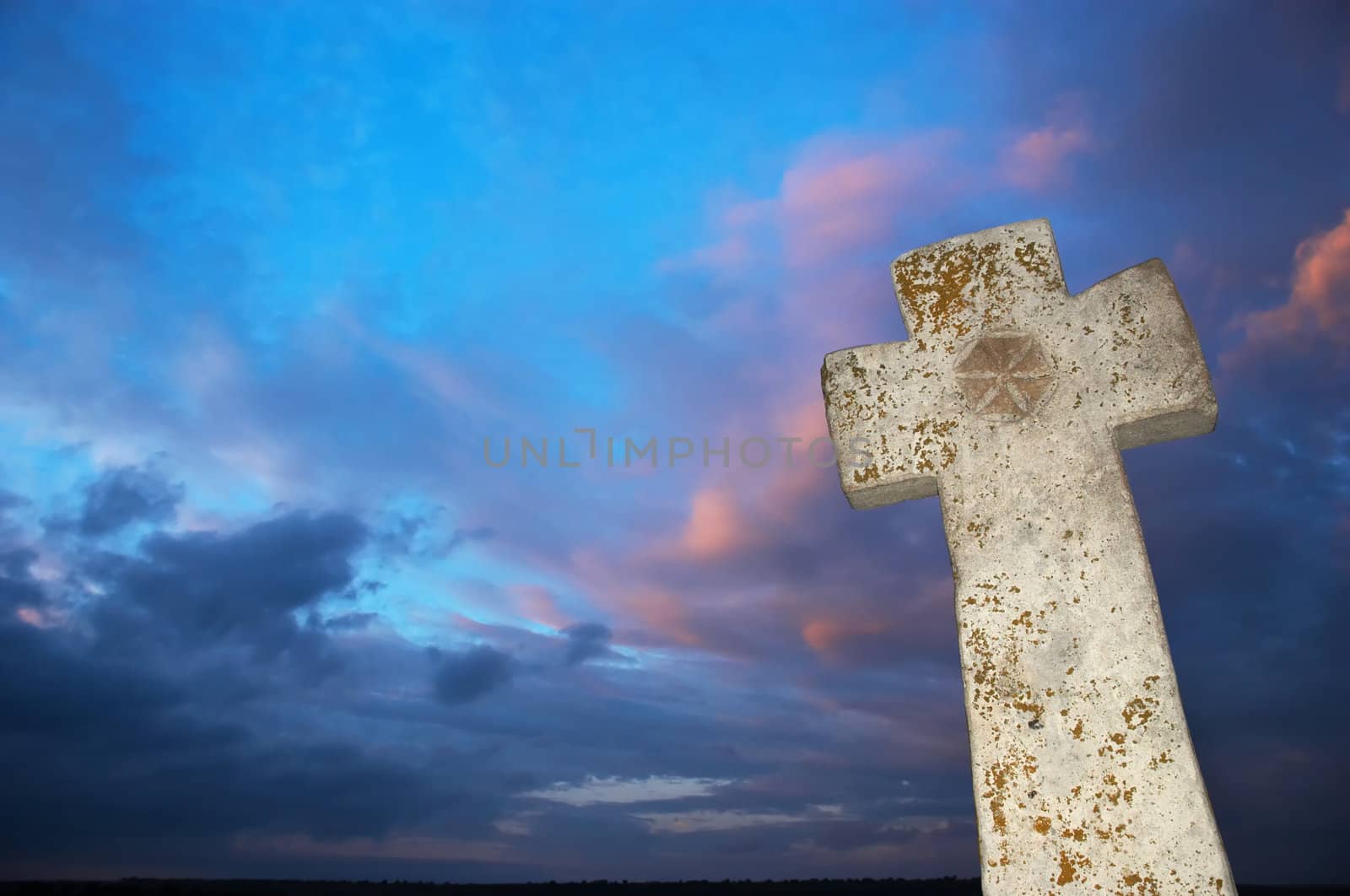 brightly lit stone cross on dark sky background