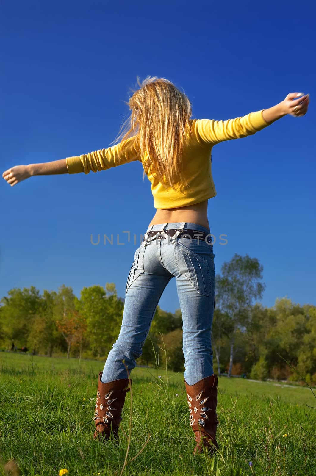 slim shaped beautiful blond girl exercising at he meadow. slight motion blur on hands