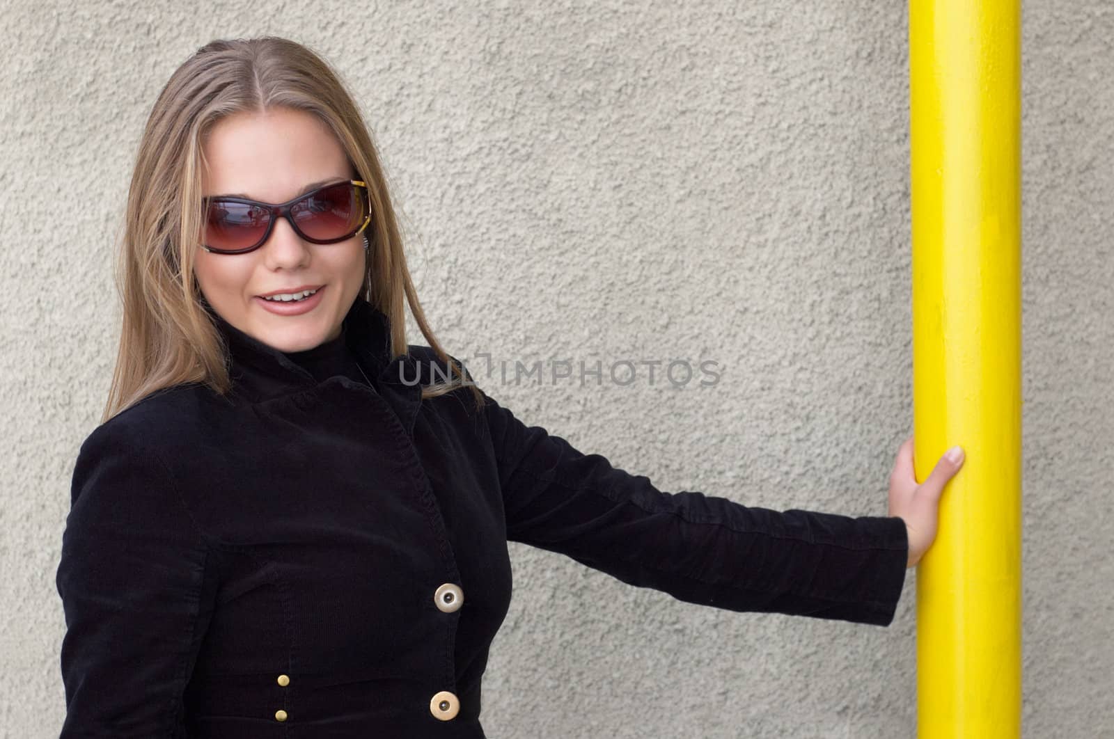 cute girl in black with sunglasses staying near the wall