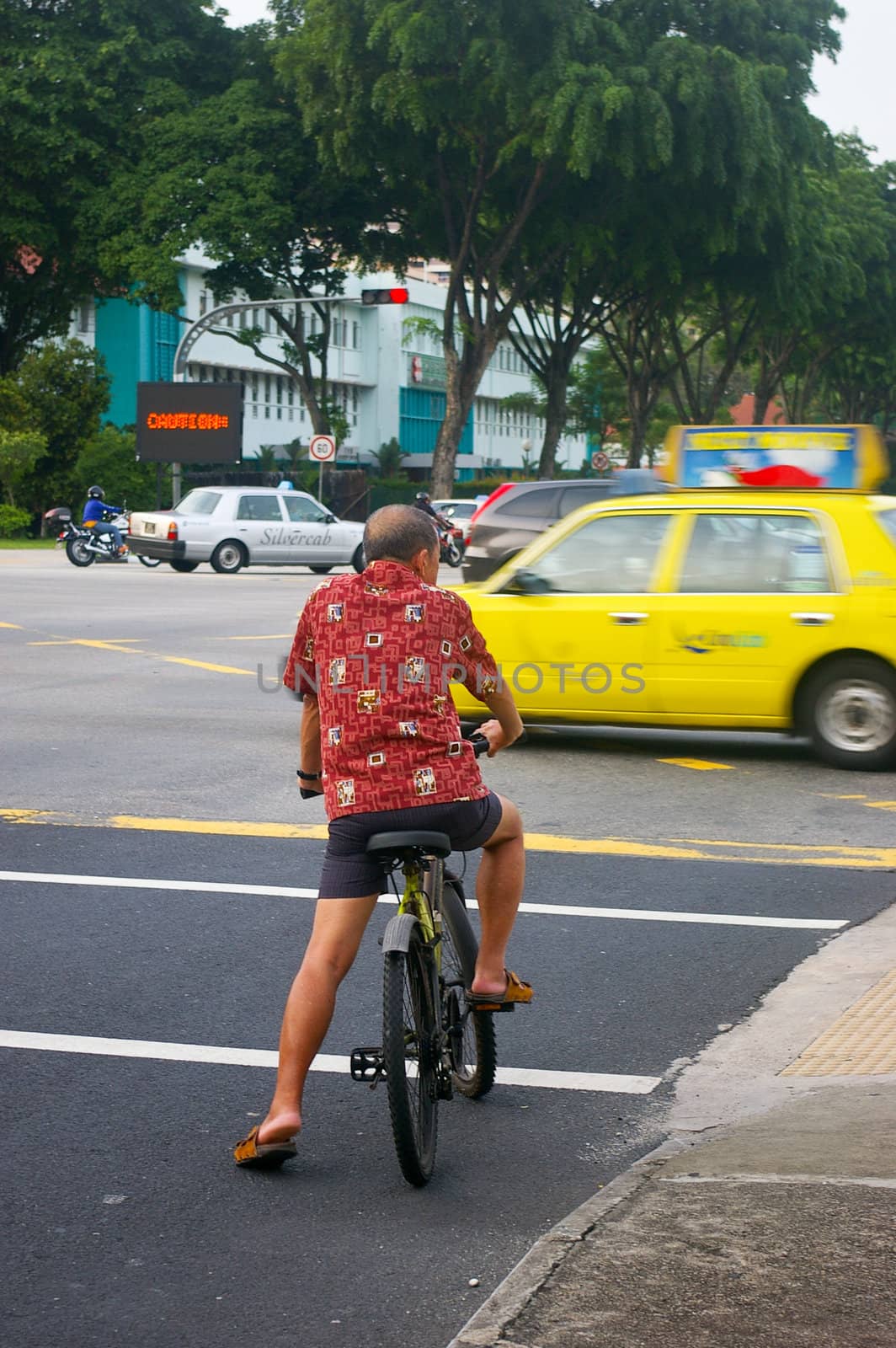 Singapore cyclist on a busy Singapore road. As public transport is becoming more expensive in Singapore, cycling is becoming the choice of transport.