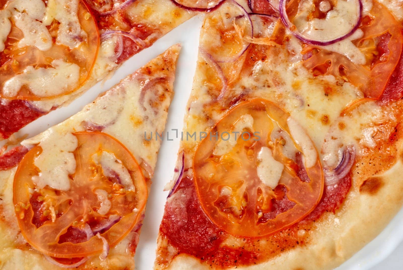 pizza closeup with salami, tomato, onion and mozzarella cheese