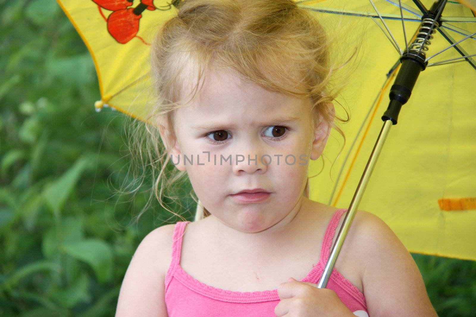 thoughtful little girl standing in the rain holding an umbrella.