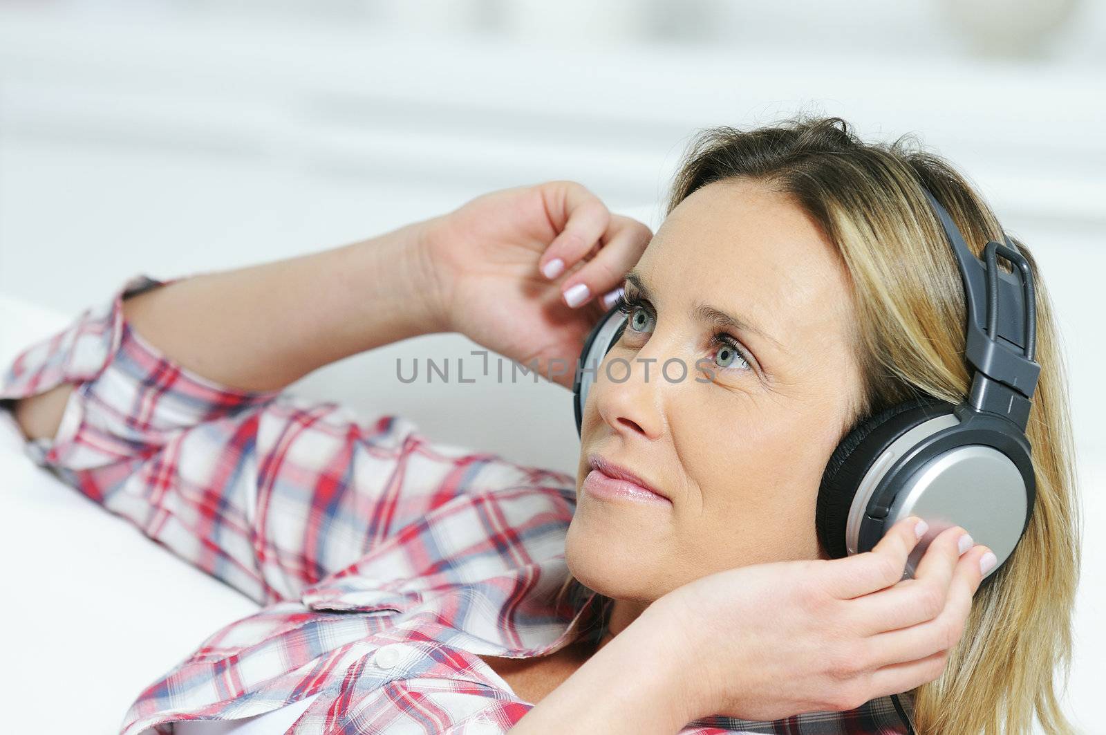 blond woman relaxing at home, listening music with a headphone