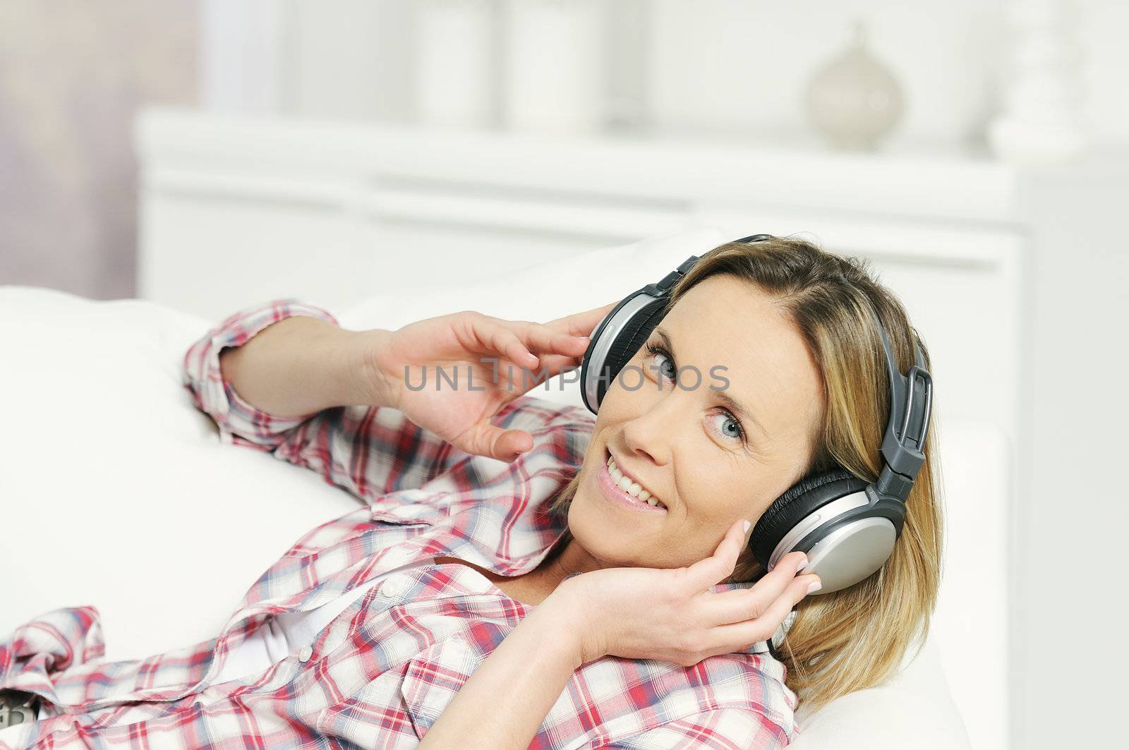 blond woman relaxing at home, listening music with a headphone
