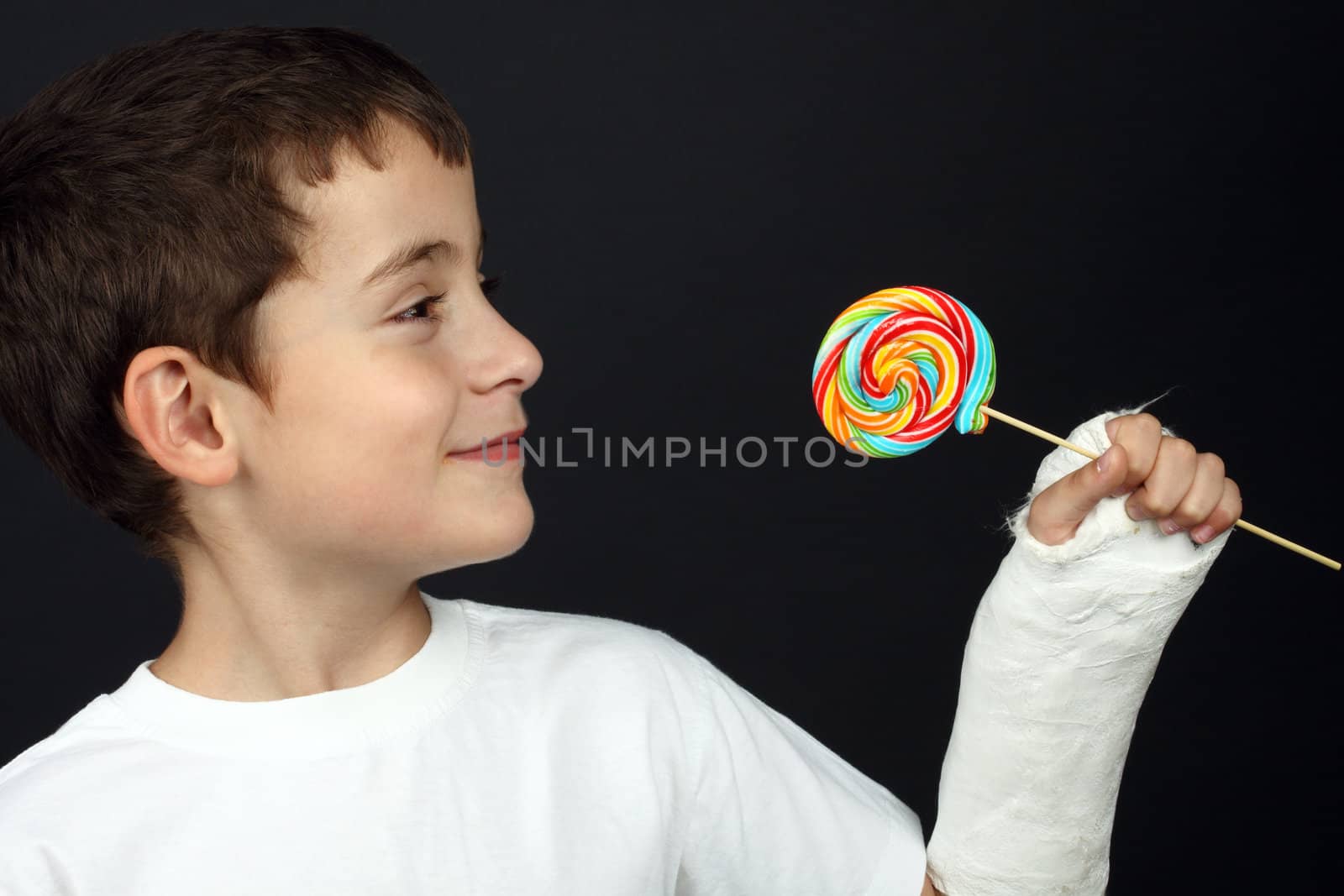 Boy with broken hand in cast, holding a lollipop