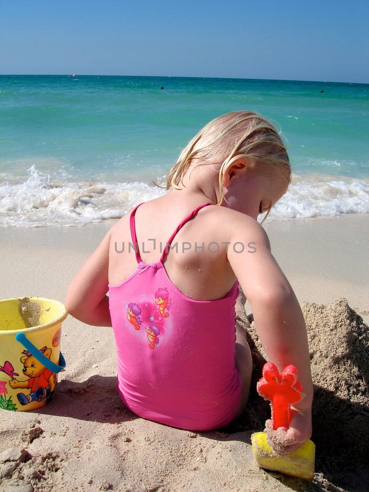 Scandinavian Lifestyle - little girl playing sand on the beach by Bildehagen