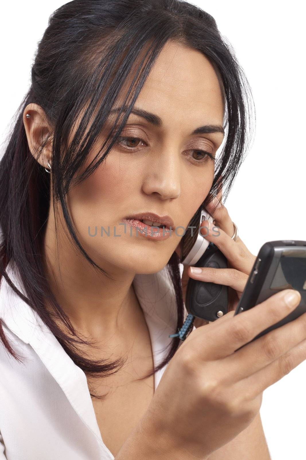 Beautiful brunette businesswoman wearing office clothes holding a couple of cellphones and keys in her hands. Isolated on white background with copy space