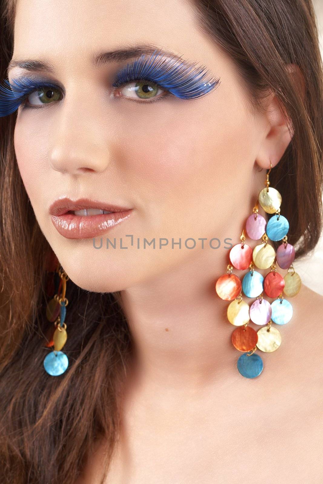 Portrait of a beautiful young brunette woman with dramatic glamour make-up and fashionable earrings