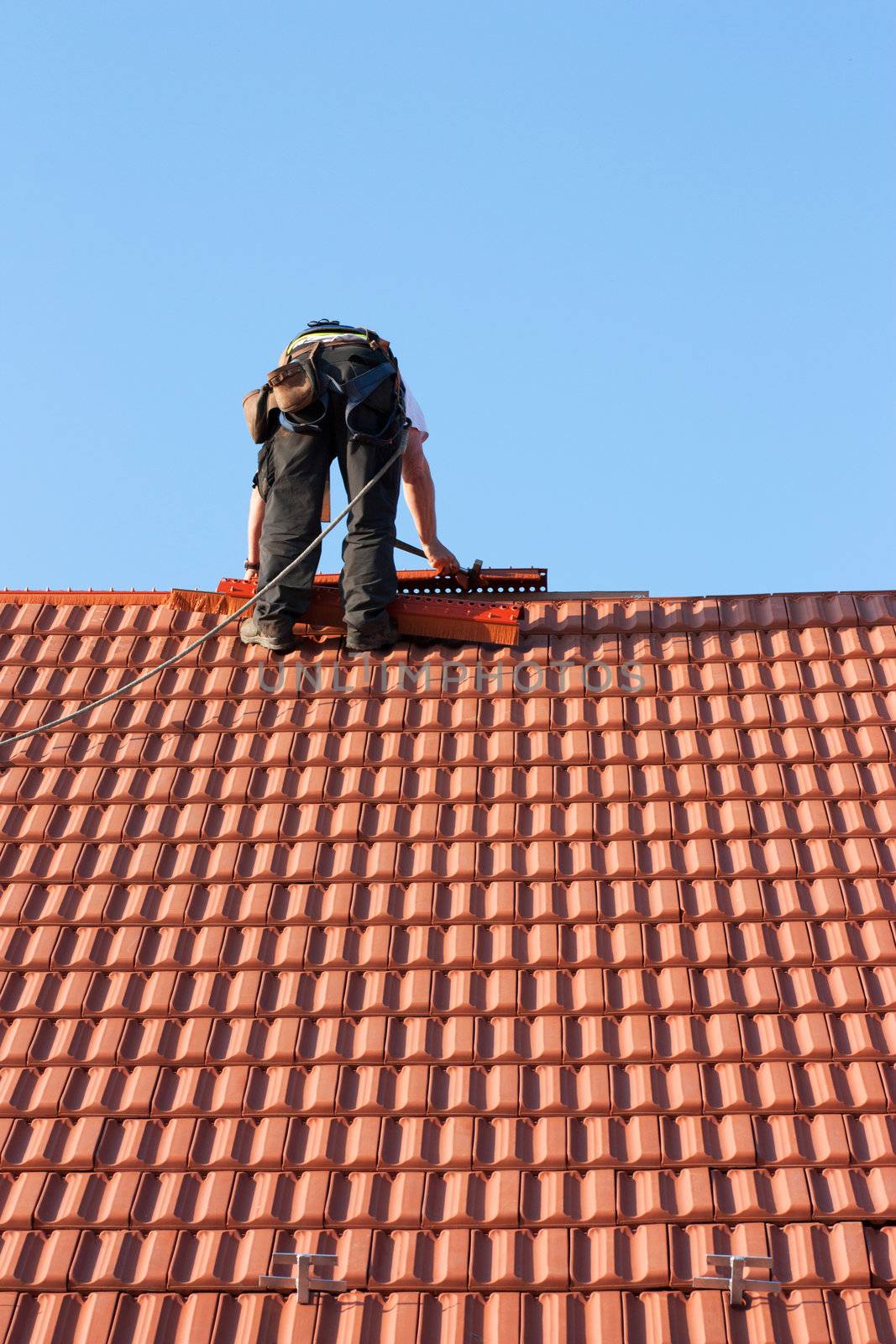 Roofer finishing laying the tiles on the roof of a building