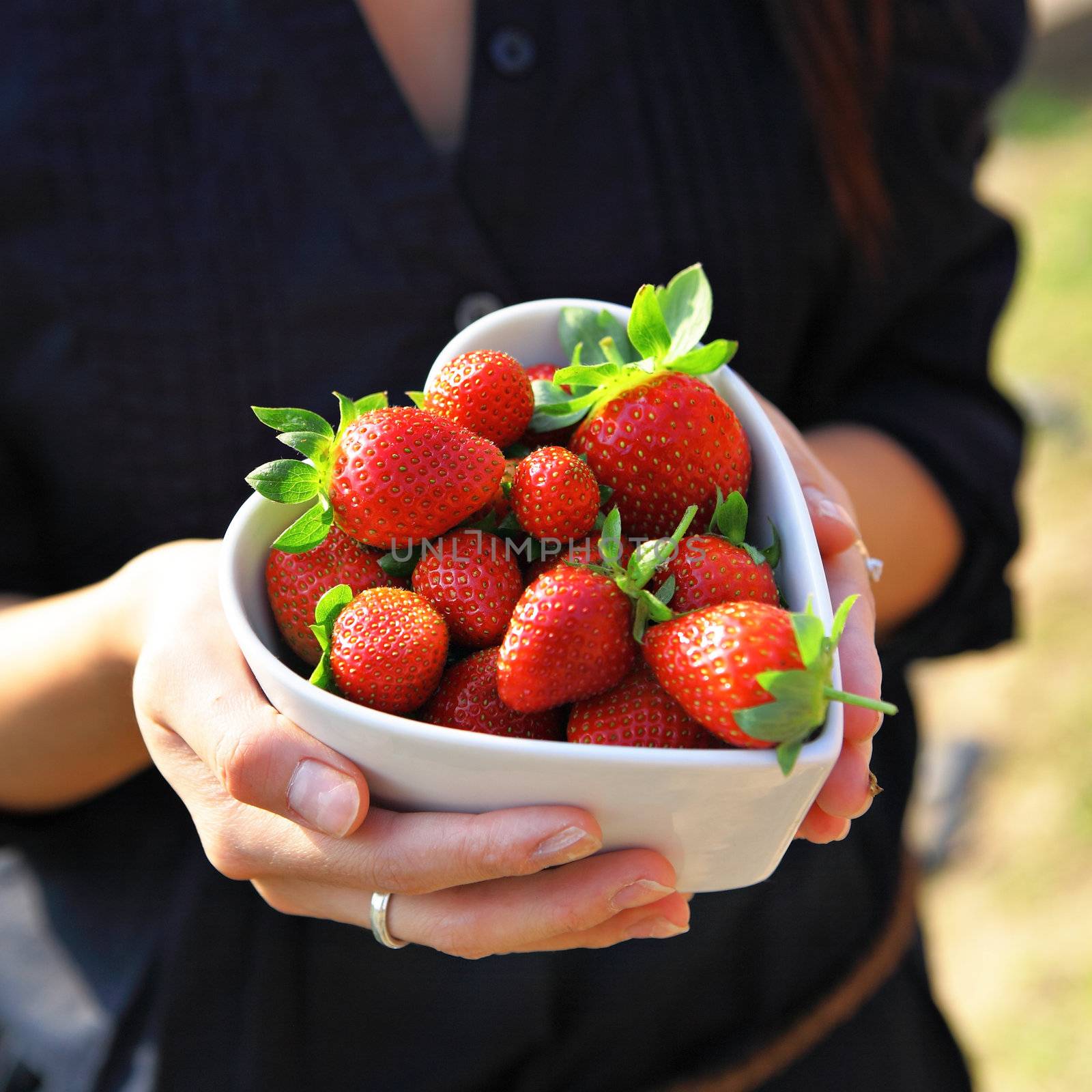 strawberry in heart shape bowl with hand by leungchopan