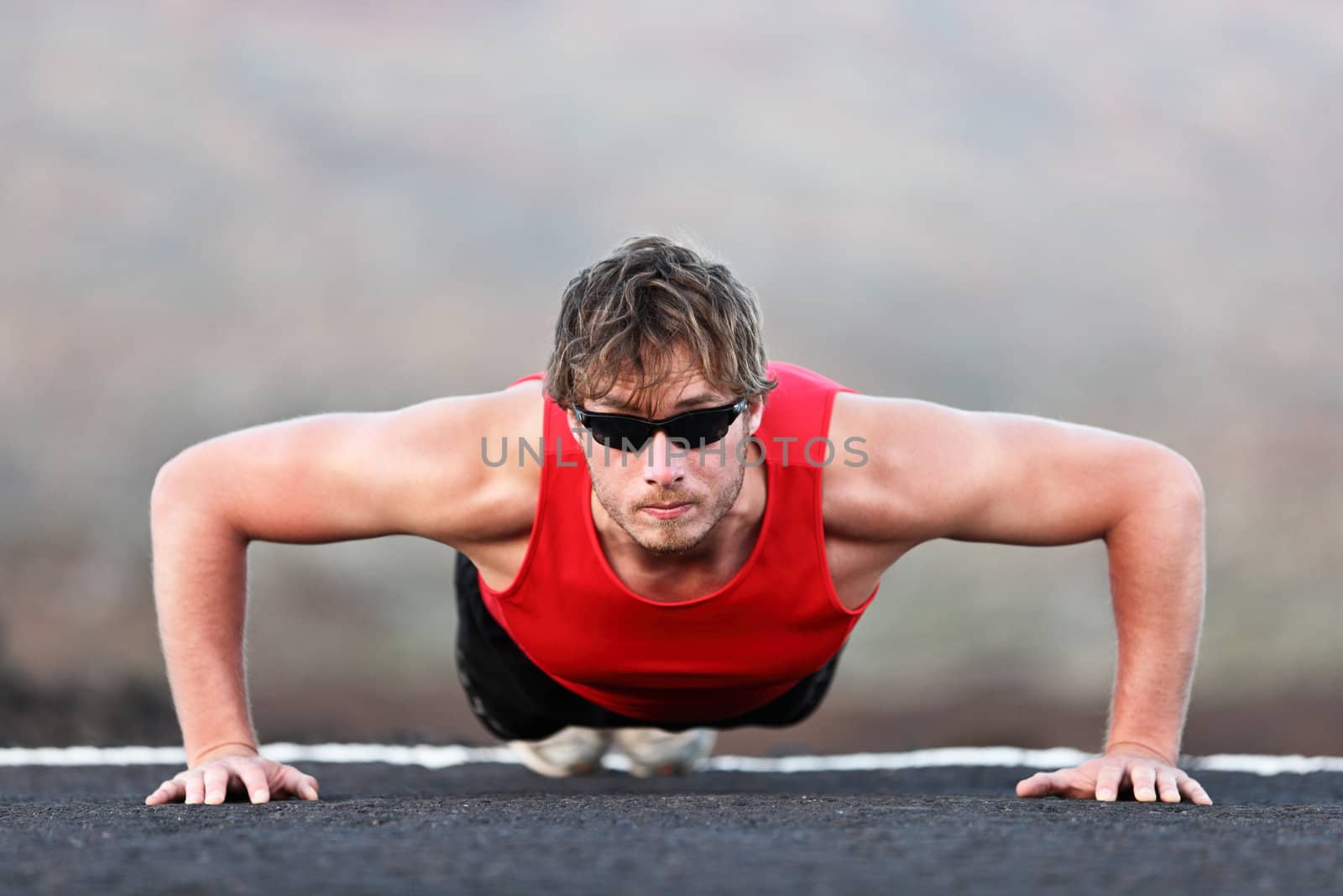 Exercise man training push ups doing strength training outdoors. Fit muscular male fitness model.