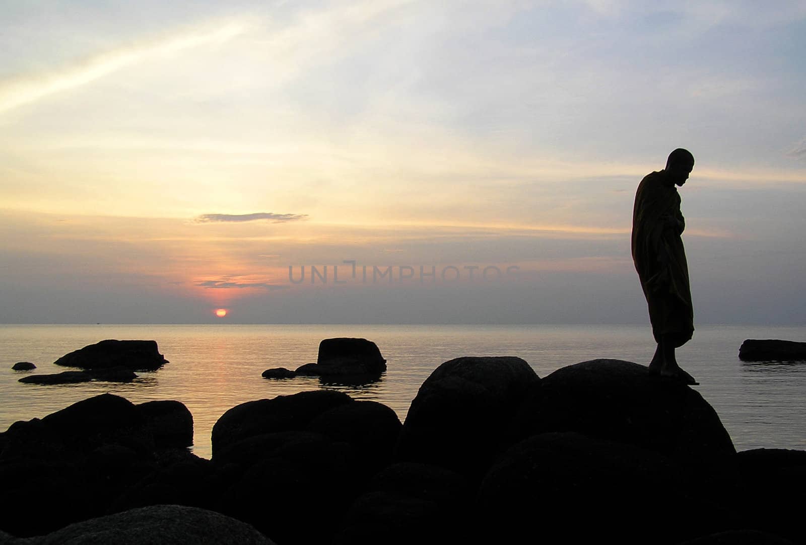 A munk wandering and meditating by the sea.