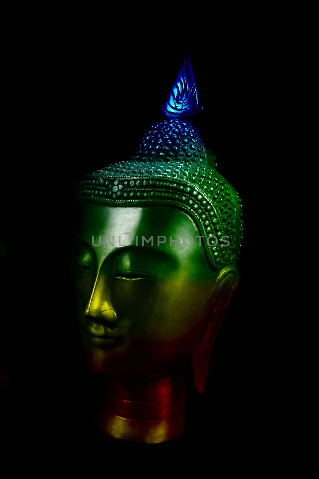 A metallic idol of a meditating Buddha in colorful light.