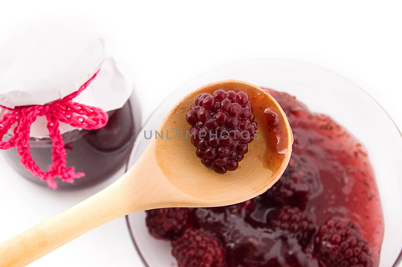 Blackberry jam in bowl and berries on plate and spoon