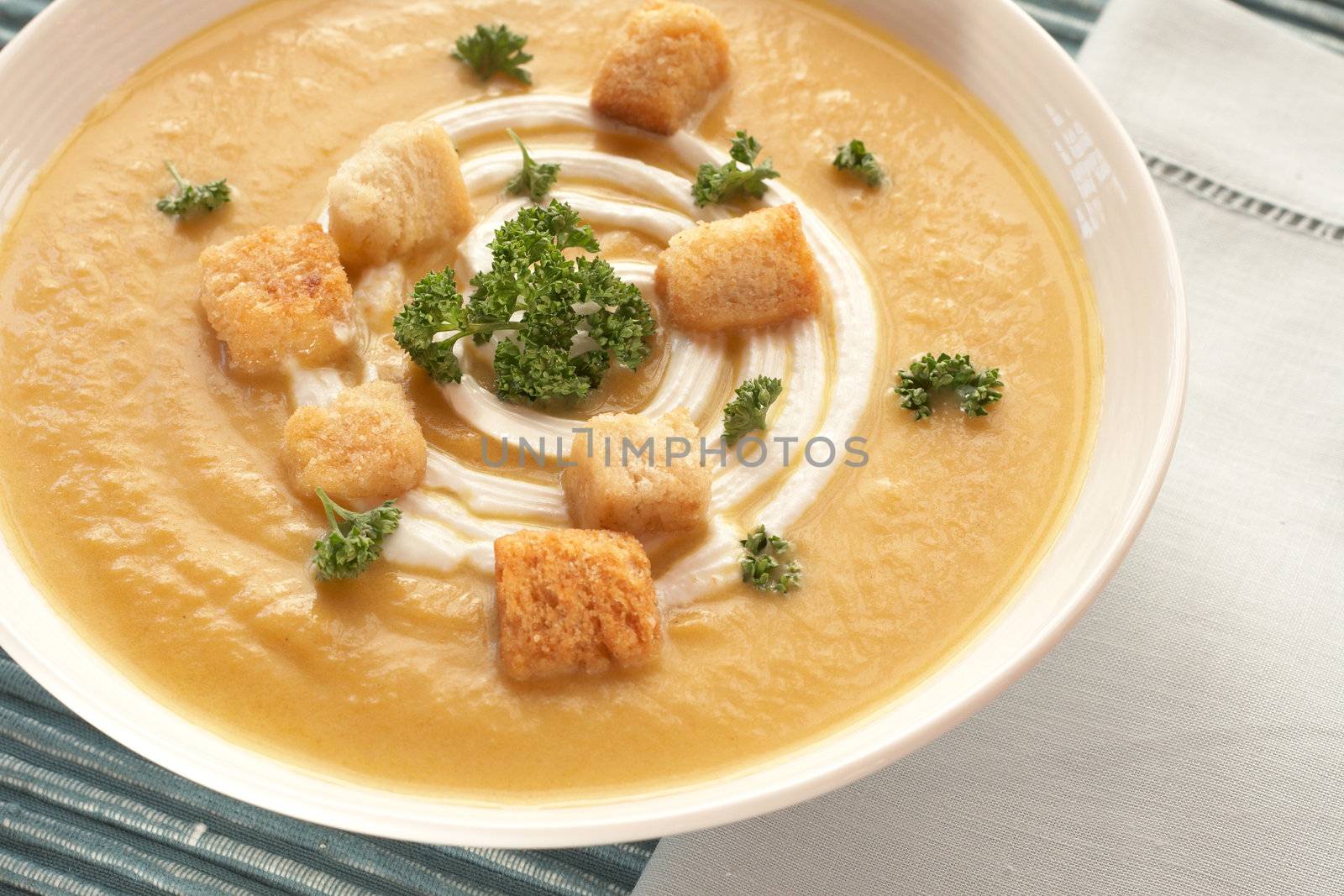 Bowl of fresh hot butternut soup with cream, parsley and croutons