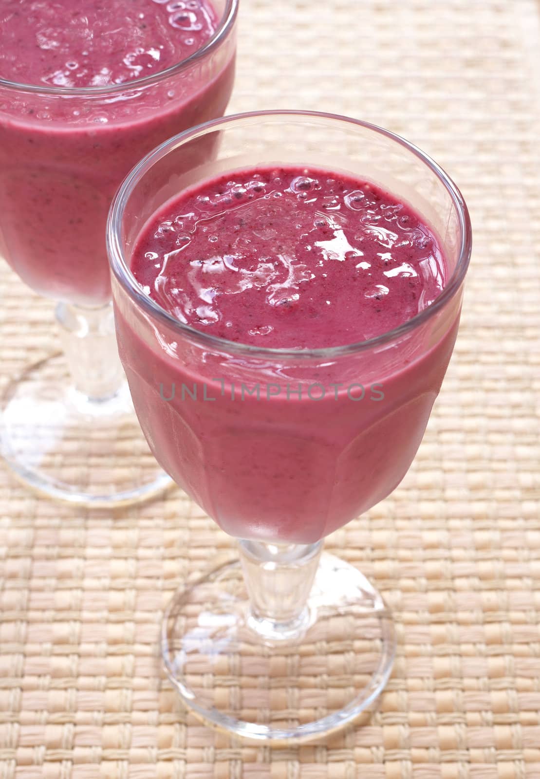 Two glasses of fresh berry smoothies on hessian placemat background