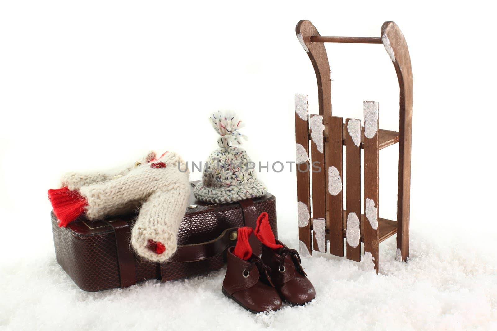 Sled, winter clothes and suitcases in front of white background