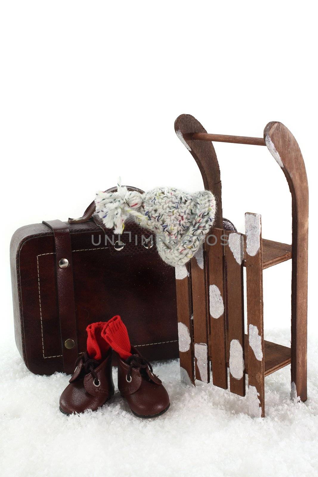 Sled, winter clothes and suitcases in front of white background