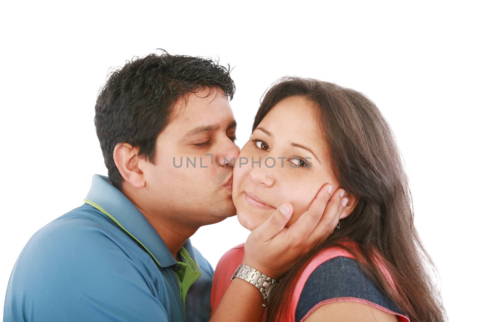 Portrait of woman looking at camera with man near by kissing her