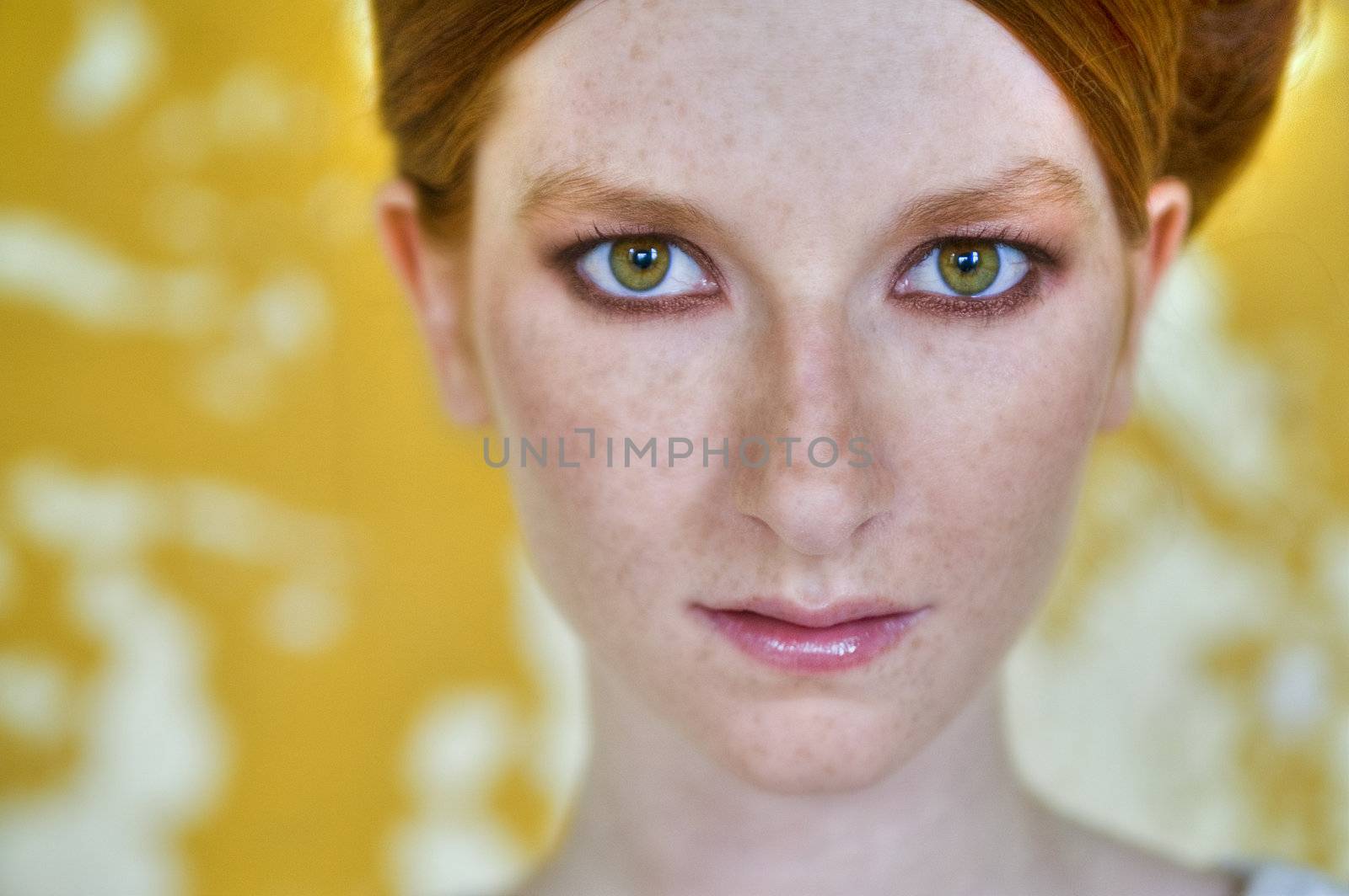 Portrait of a natural redhead in front of a yellow wall